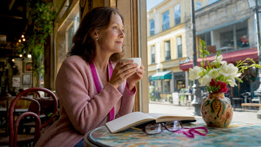 Middle-aged woman holding coffee at kitchen table