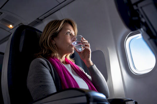 Woman drinking water aboard an airplane
