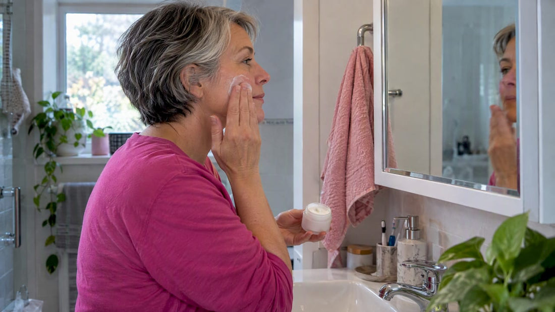 Midlife woman applying moisturizer to her cheek
